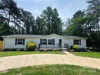 Charming single-story home with blue shutters, manicured landscaping, and concrete driveway at 166 Brook Creek Dr, Troutman, NC 28166
