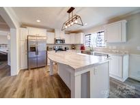 Bright kitchen featuring white cabinets, stainless steel appliances, and a large island with a marble countertop at 185 Crystal Bay Dr, Mooresville, NC 28115