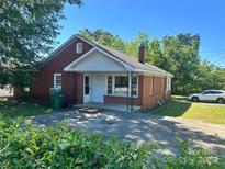 Charming red brick home featuring a cozy front porch and well-maintained yard and driveway at 301 Louise St, Lancaster, SC 29720
