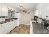 Functional kitchen with white cabinetry, laminate counters, and tile floors at 515 Burlington St, Wadesboro, NC 28170