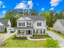 Inviting two-story home featuring stone accents, black shutters, covered porch, and lush landscaping at 121 Pine Eagle Dr, Rock Hill, SC 29732