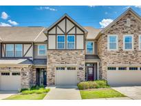 Charming townhome featuring a stone and siding exterior with attached garage under a clear blue sky at 1213 Bhaltair Ln, Fort Mill, SC 29708