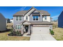 Charming two-story home with stone accents, inviting entrance, and attached two-car garage at 154 Rooster Tail Ln, Troutman, NC 28166