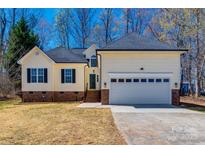 Inviting yellow home with a two-car garage, black shutters, and brick accents on the exterior at 937 Brooklee Dr, Kings Mountain, NC 28086
