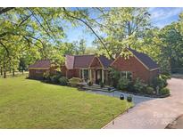 Charming red brick home with mature trees, lush green lawn and meticulous landscaping creating serene curb appeal at 1500 Griffith Rd, Monroe, NC 28112