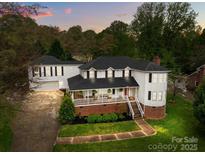 Charming two-story home with a brick foundation, white siding, covered front porch, and a separate two-car garage at 16421 Breckshire Dr, Huntersville, NC 28078