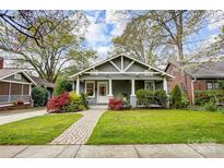 Charming gray home with a brick walkway, manicured lawn, and colorful landscaping, creating curb appeal at 1717 Thomas Ave, Charlotte, NC 28205