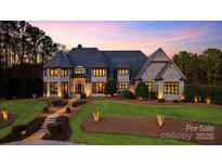 Stunning stone home with lush lawn, elegant landscaping, and warm lighting at dusk at 525 Lake Lynn Rd, Concord, NC 28025