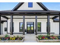 Inviting front porch with black accents, decorative columns, and colorful flowerbeds enhances curb appeal at 7419 Tesh Rd, Monroe, NC 28110