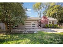 Charming home with a red chimney and covered patio, surrounded by lush greenery at 842 E Woodlawn Rd, Charlotte, NC 28209