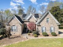 Beautiful brick home with manicured lawn, mature landscaping, and solar panels on a sunny day at 124 Cedar Woods Dr, Mooresville, NC 28117