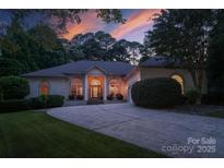 Elegant home exterior featuring a circular driveway, arched windows, and inviting front entrance at dusk at 2587 Penngate Dr, Sherrills Ford, NC 28673