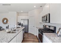 Modern kitchen with stainless steel appliances, granite counters, white cabinets and hardwood floors at 882 Two Brothers Ln, York, SC 29745