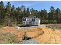 New two-story home featuring white siding, gray accents, and a wooded backdrop, in early stage of construction at 1259 Willow Grove Ln # 100, York, SC 29745