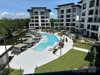 Upscale community pool area with several covered lounging areas and manicured green spaces between modern condo buildings at 19329 Watermark Dr # 142, Cornelius, NC 28031