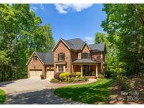 Charming two-story brick home with a covered porch, lush landscaping, and a three-car garage at 4273 Stormy Pointe Ct, Denver, NC 28037