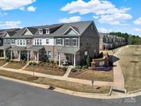 A row of beautifully designed townhomes in Mc Ewen Village with manicured lawns and charming facades at 8004 Whitegrove Rd, Charlotte, NC 28227