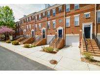 Brick townhomes with garage, stoop, and black trimmed doors in a row, with green bushes and tree in landscape at 1122 Dean Hall Ln, Matthews, NC 28105
