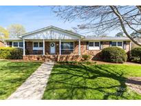 Charming brick home with a welcoming front porch and manicured lawn on a sunny day at 1228 Graystone Dr, Gastonia, NC 28054