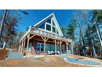 Striking lake house with a large deck, fire pit, and a wall of windows to maximize the lake view at 22970 Lake Tillery Rd, Albemarle, NC 28001