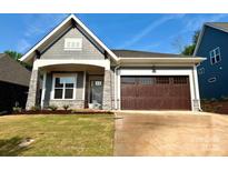 Charming home featuring stone accents, a covered porch, and a two-car garage at 174 Fulworth Nw Dr # 65, Concord, NC 28027