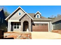 Charming home featuring stone accents, a two-car garage, and inviting curb appeal against a bright blue sky at 178 Fulworth Nw Dr # 64, Concord, NC 28027