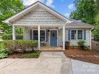 Charming home featuring a cozy covered porch, blue shutters, and a beautifully landscaped front yard at 2214 Olde Chantilly Ct, Charlotte, NC 28205