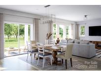 Open-concept dining area featuring a wooden table, stylish chairs, and abundant natural light at 7027 Short Stirrup Ln, Mint Hill, NC 28227