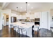 Bright kitchen with white cabinetry, large island with seating, and stainless steel appliances at 11144 Limehurst Pl, Charlotte, NC 28278