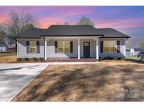 Charming gray home with a black roof, complemented by professionally landscaped yard and a spacious concrete driveway at 206 W 19Th St, Kannapolis, NC 28081