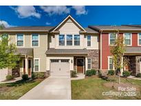 Charming townhome with attached garage, stone accents and landscaped yard on a beautiful partially cloudy day at 319 Pond Place Ln, Matthews, NC 28104