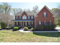 Charming two-story red brick home with a welcoming front porch and well-maintained landscaping at 8004 Talcott Dr, Mint Hill, NC 28227