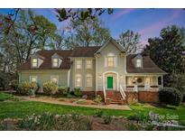 Charming home featuring a manicured lawn, lush landscaping, and a welcoming front porch with green door at 3717 Bodenham Ct, Charlotte, NC 28215