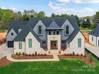 Beautiful exterior elevation showcasing brick, siding, well manicured landscaping, and a lush green lawn at 406 Sugar Maple Ln, Weddington, NC 28104