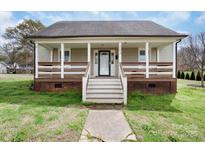 Charming home featuring a quaint front porch with brick foundation and a well-maintained lawn at 203 Jackson St, Fort Mill, SC 29715