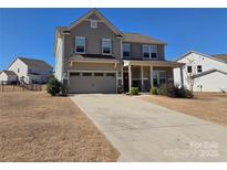Two-story home featuring a two-car garage, covered front porch, and well-maintained landscaping against a clear blue sky at 4630 Bent Green Ln, Monroe, NC 28112