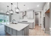 New kitchen features light gray cabinets, stainless appliances, a pantry and an island with sink and pendant lighting at 9934 Cask Way, Huntersville, NC 28078