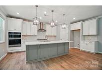 Bright kitchen features a gray island, stainless appliances, pendant lighting, and white cabinetry at 9957 Cask Way, Huntersville, NC 28078