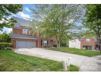Charming brick home featuring a two-car garage, mature tree, and a well-maintained front yard at 10418 Goosefoot Nw Ct, Concord, NC 28027