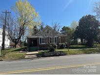 Charming home with mature trees and landscaping, complemented by a blue sky backdrop at 201 W Main St, Lincolnton, NC 28092