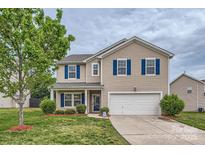 Charming two-story home boasts blue shutters, a well-manicured lawn, and attached two-car garage at 4026 Clover Nw Rd, Concord, NC 28027