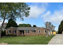 Charming single-story brick home with a well-manicured lawn and mature trees at 5119 Blackberry Ln, Matthews, NC 28104