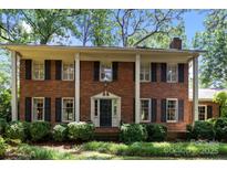Charming red brick home featuring stately white columns and dark shutters surrounded by lush landscaping at 5510 Sardis Rd, Charlotte, NC 28270