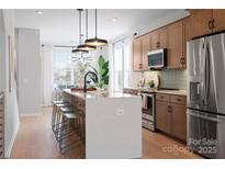 Bright kitchen features a large island with seating, stainless steel appliances, and modern light fixtures at 5604 Kingspan Dr, Charlotte, NC 28217
