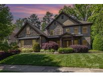 Stone two-story home featuring manicured landscaping and a covered front porch at 5706 Sardis Hall Ct, Charlotte, NC 28270