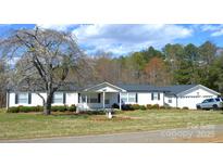 Charming single-story home with white siding, dark shutters, well-manicured lawn and mature landscaping at 648 Dobson Farm Rd, Statesville, NC 28625