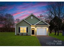 Charming single-story home with a well-maintained lawn, garage, and inviting facade set against a colorful sky at 1026 Dooley Dr, Charlotte, NC 28227