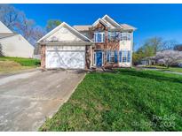 Two-story home with brick details, blue shutters, attached garage, and a well-maintained front yard at 14802 Rolling Sky Dr, Charlotte, NC 28273