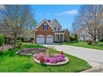 Charming two-story brick home featuring a two-car garage and beautifully landscaped front yard with vibrant flowers at 2740 Cameron Commons Way, Matthews, NC 28104