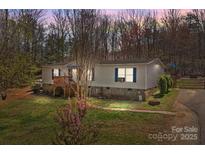 Charming single-story home with a wooden porch, stone foundation and mature trees in a wooded setting at 4793 Appaloosa Ln, Maiden, NC 28650